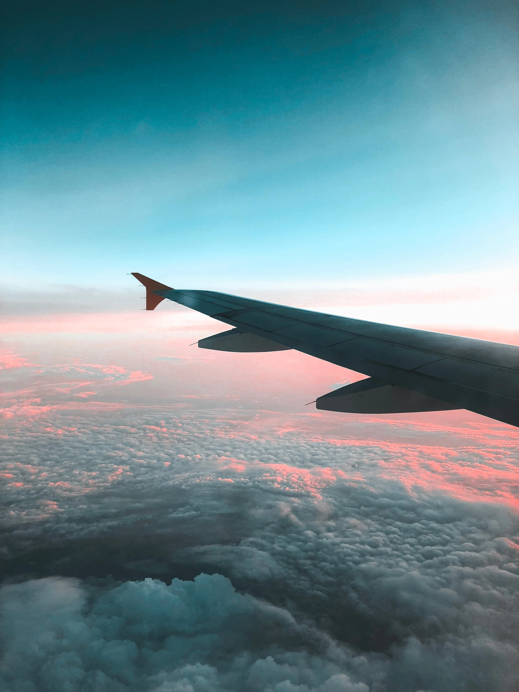 An aircraft wing above clouds in warm evening light